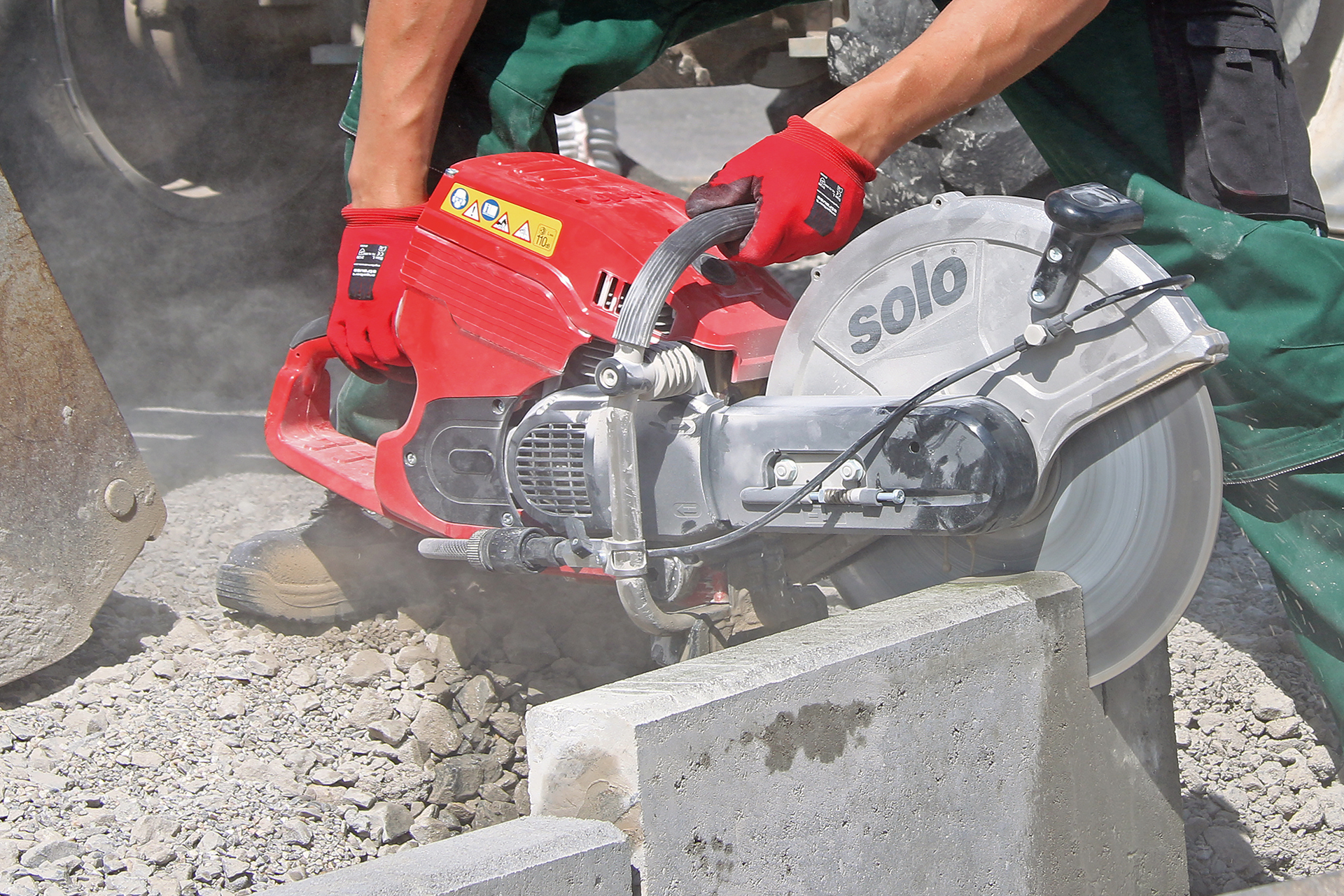 Eine Person arbeitet mit einem SOLO-Trennschleifer, um einen Betonblock auf einer Baustelle zu durchtrennen. Es entstehen Staub und Schmutz bei der Arbeit.